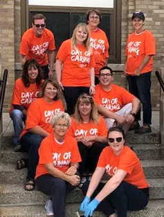 Andis Associates sitting on steps in orange shirts volunteering for Day of Caring
